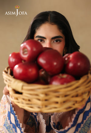 Asim Jofa AJUBC-05 campaign portrait – model holding a basket of red apples in front of her peach and blue printed lawn shirt