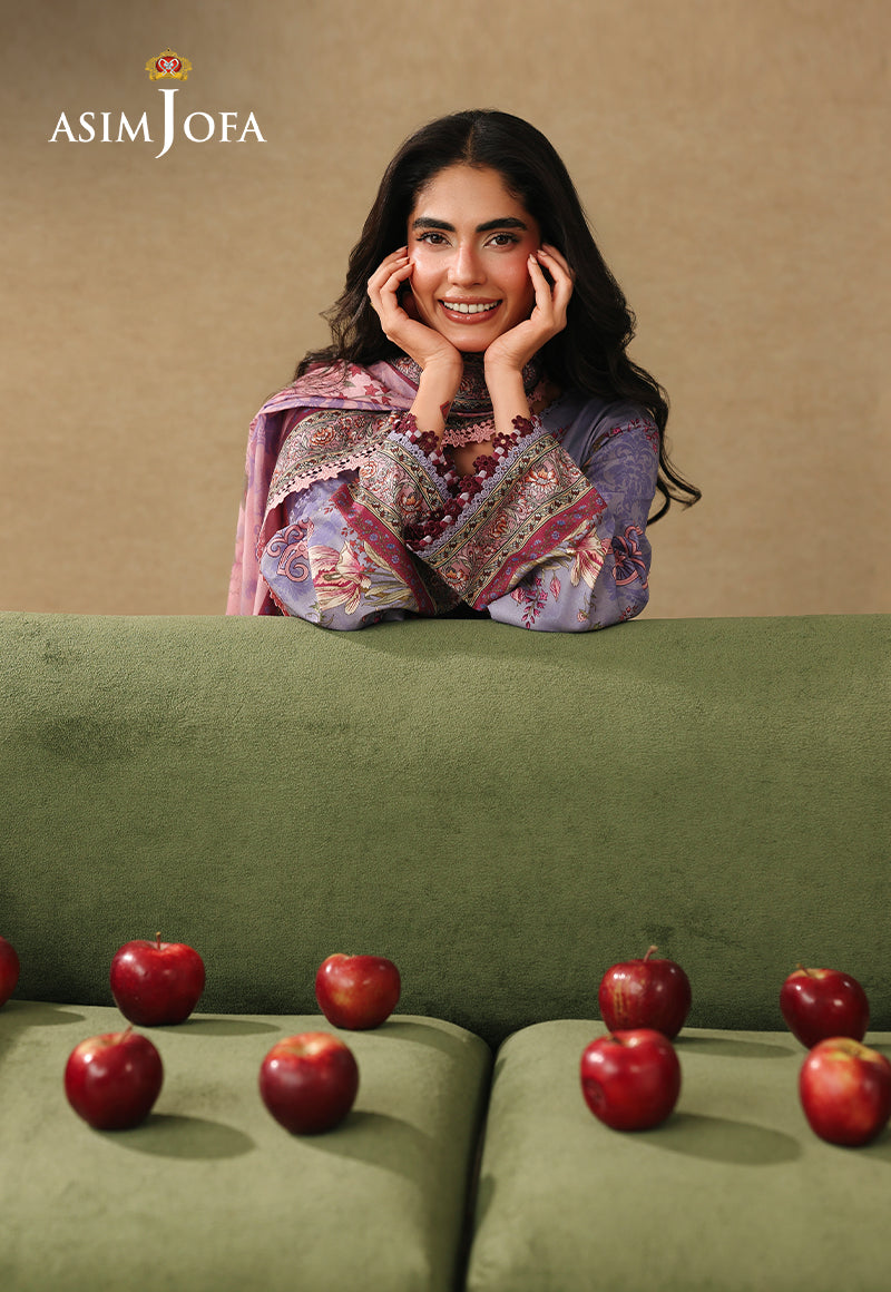 Asim Jofa AJUBC-06 lilac floral printed lawn shirt – smiling model leaning over a green sofa, showing patterned cuffs