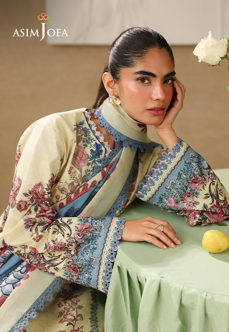 Asim Jofa AJUBC-07 printed lawn campaign portrait – model resting on a table, with blue floral cuff beside yellow lemons